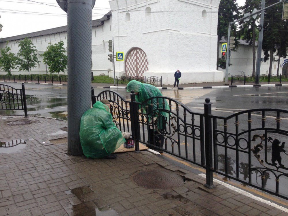 Фото дня. Рабочие в дождь красят заржавевшие заборы с медведями вокруг Богоявленской площади